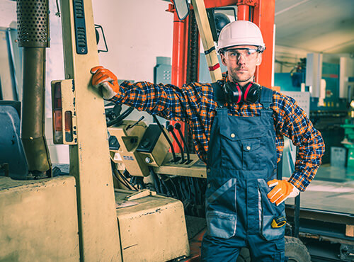 Lärm in Industriehalle und Werkstatt Ein Arbeiter mit Gehörschutz steht in einer lauten Industriehalle oder Werkstatt.