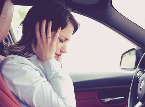 Eine Frau versucht sich vor Lärm im Auto zu schützen.