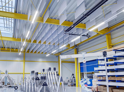 Akustikdecke als Schallschutz in einer Industriehalle. Schallabsorber hängen an der Decke einer Industriehalle und reduzieren Lärm.