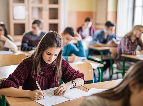 Schallschutz in der Schule hilft bei Lernen und konzentrierten Arbeiten. Ein Mädchen arbeitet konzentriert im Klassenraum einer Schule mit Schallschutz und Lärmschutz.