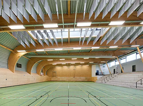Freischwebende Schallabsorber unter der Hallendecke einer Sporthalle senken den Lärmpegel und reduzieren Hall.