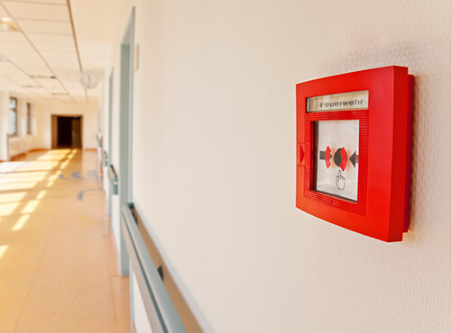 Brandschutz und Lärmschutz in Schulen und Kindertagesstätten Ein Feuermelder auf dem Flur einer Schule mit Schallschutz und Schalldämmung